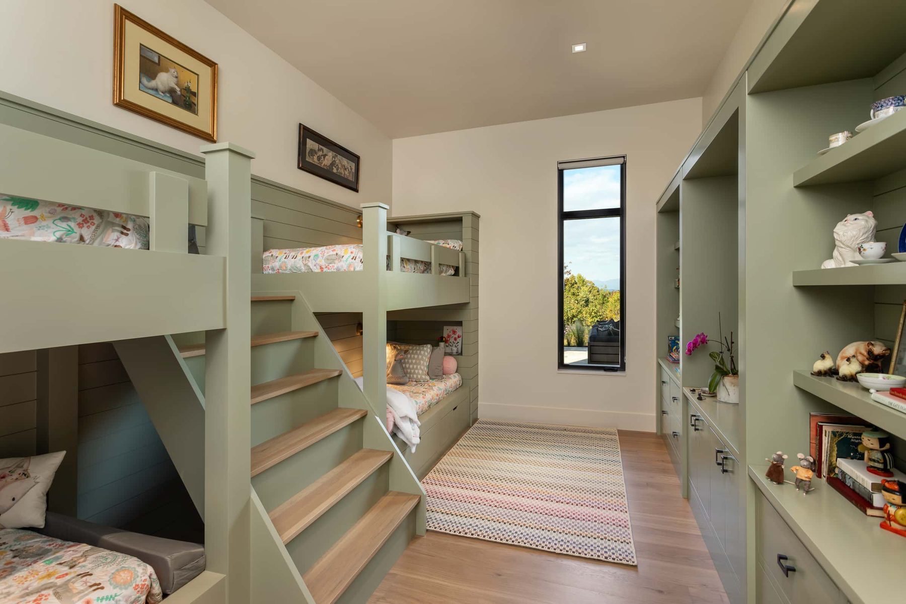 Sage bunk room with built-in stairs and shelving