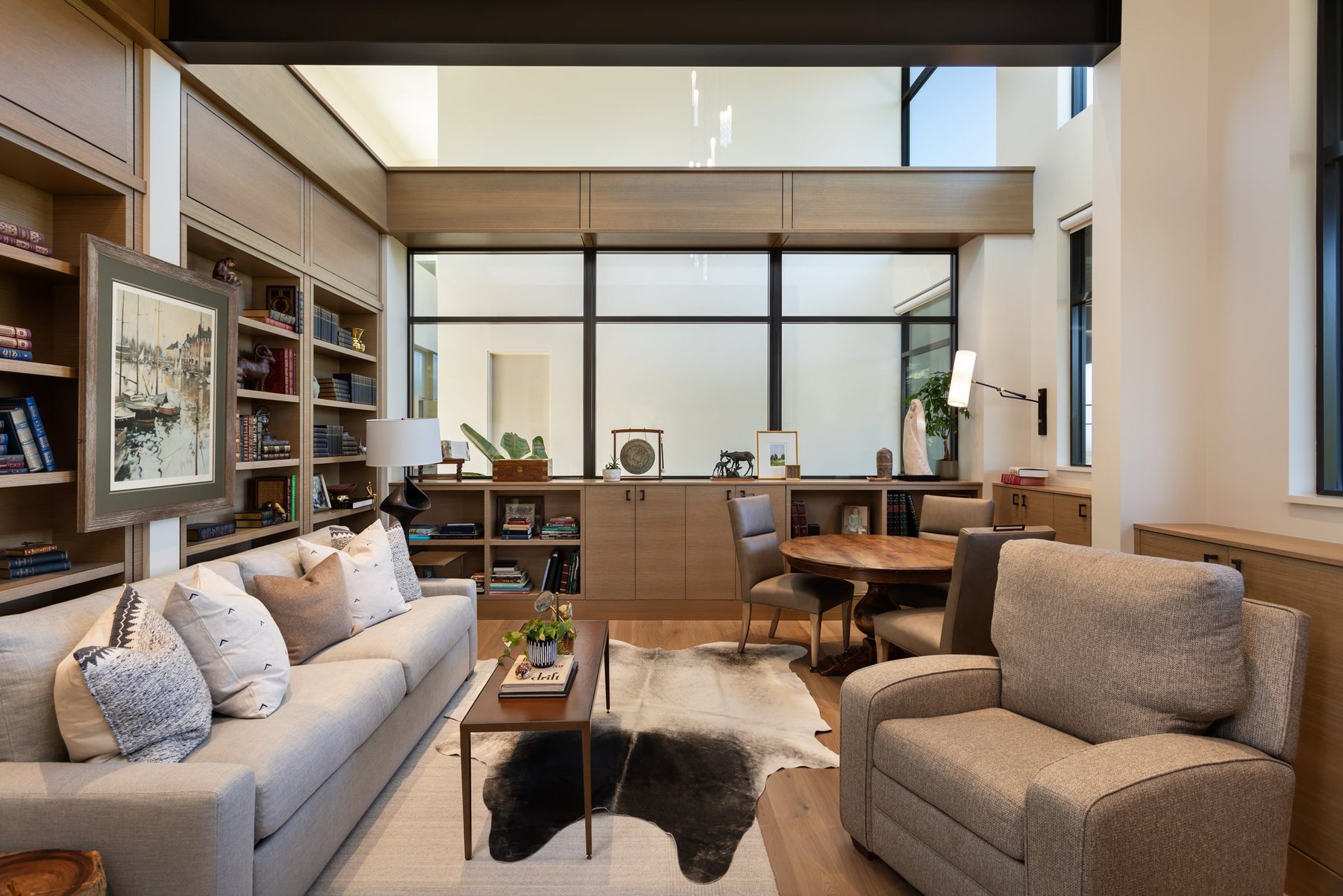 Library with oak bookcases, paneled walls and low cabinets beneath a window wall